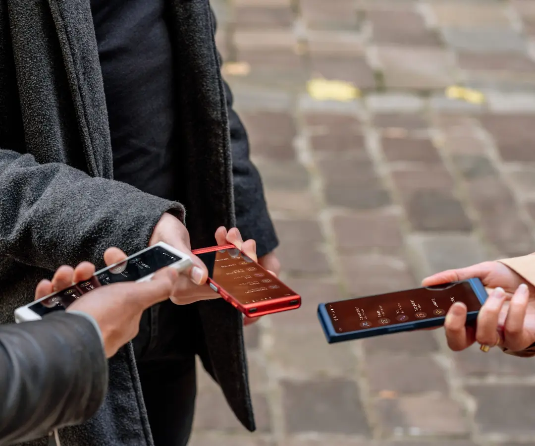 Trois amis tenant joyeusement leurs traducteurs, engagés dans la conversation et partageant des moments ensemble. 