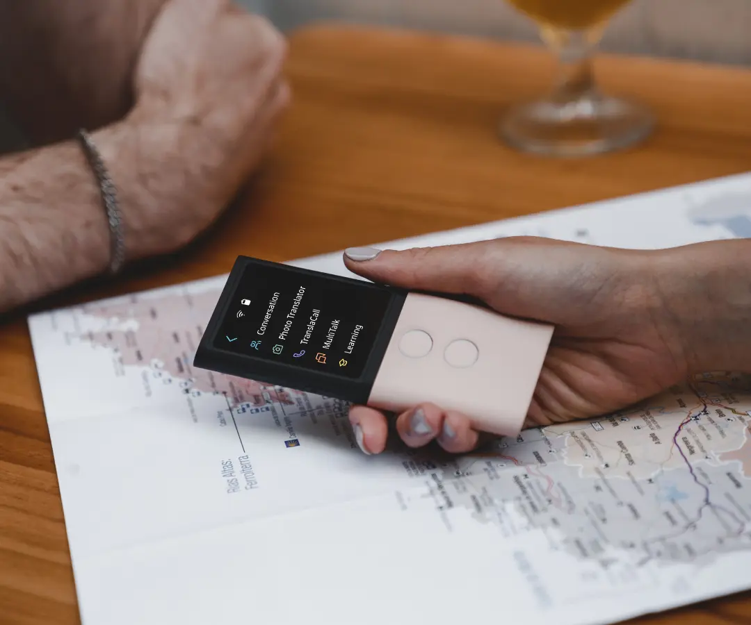 Gros plan d’une main tenant un traducteur au-dessus d’une table sur laquelle se trouve une carte